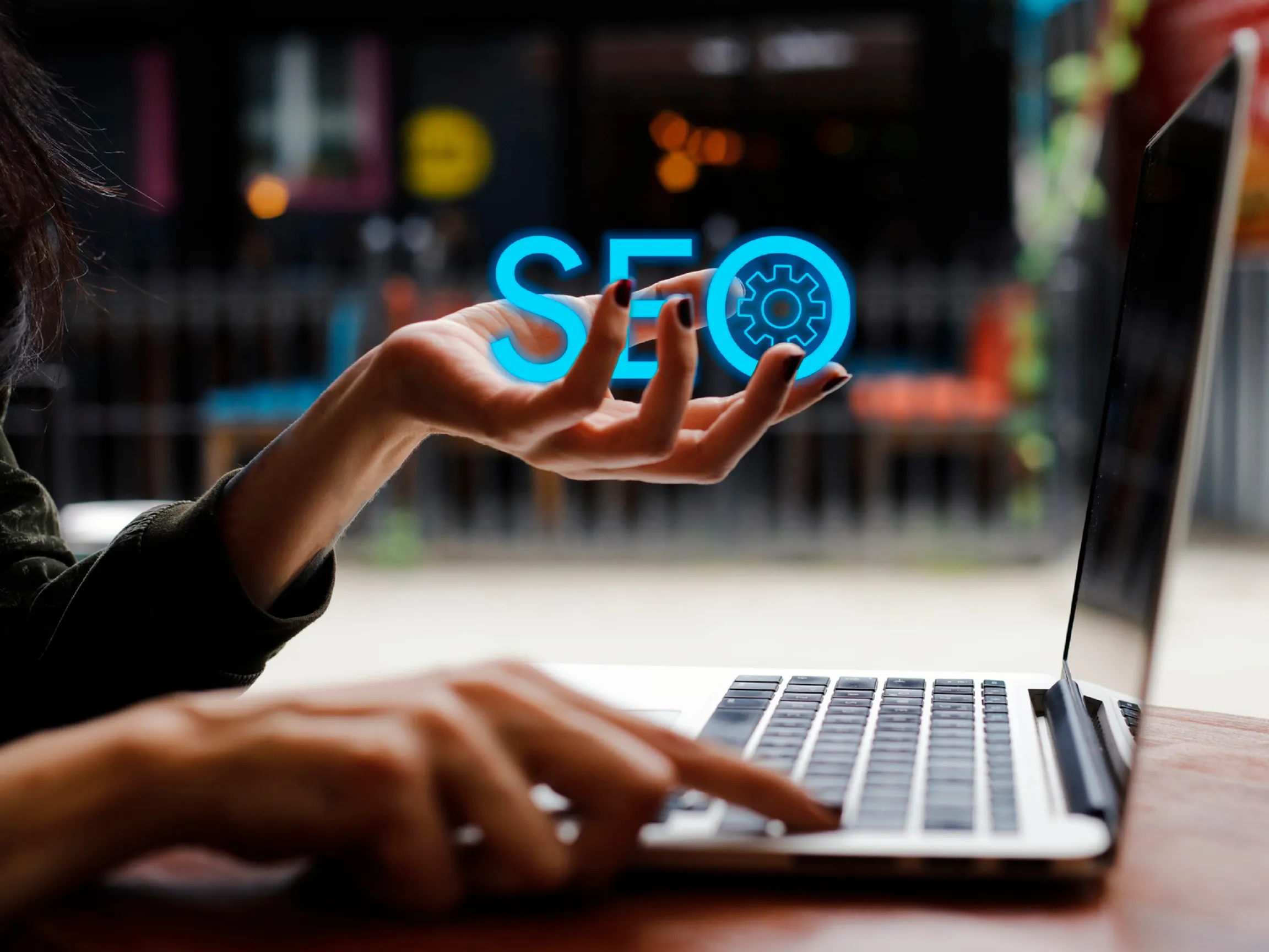 Handing holding the letters "SEO" while using a laptop - what does SEO mean?