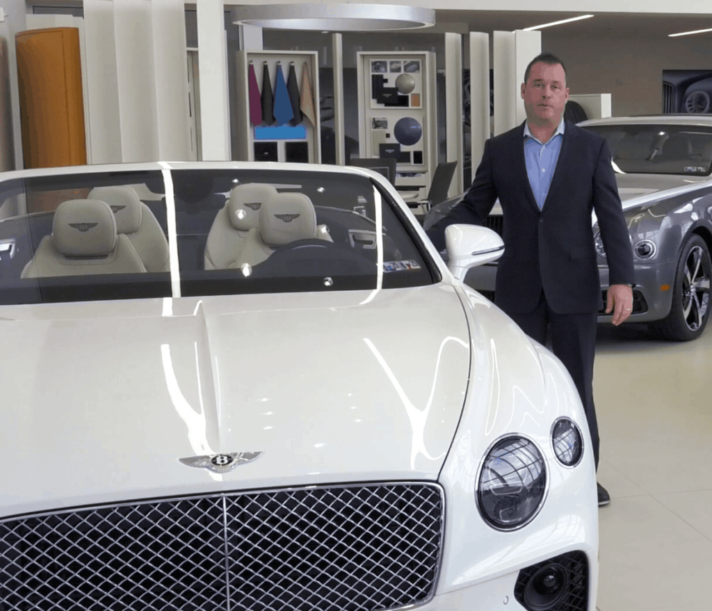 car dealership blog - salesman standing next to white bentley car