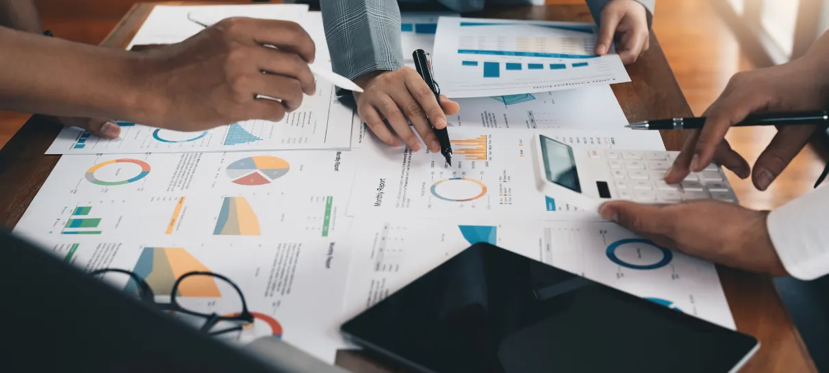 marketing team with scattered papers of data and analytics across table