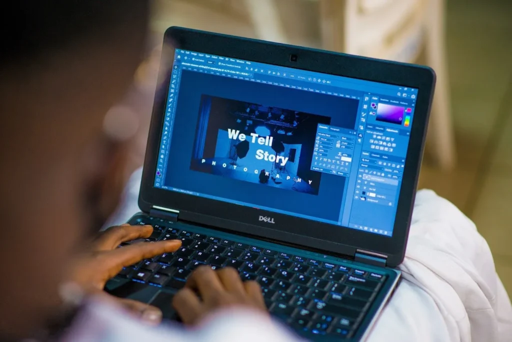 Person sitting at computer creating a graphic that says "We Tell A Story"