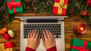 Holiday Advertising Strategy - Hands typing on laptop surround by Christimas and Holiday decor on table